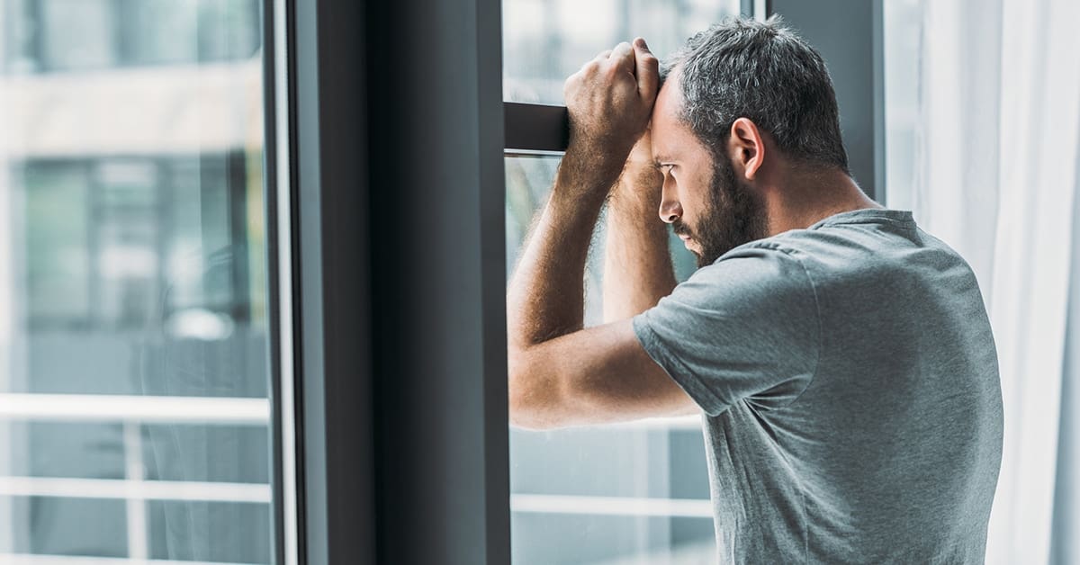 depressed man looking through window