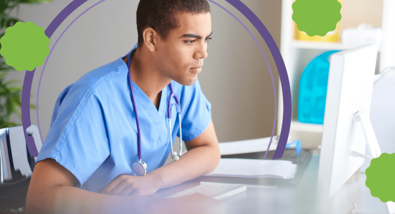 A male in scrubs looking at a computer