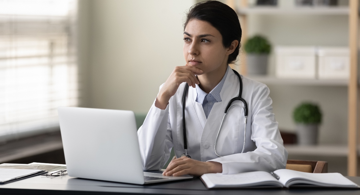 female doctor sitting at a desk looking thoughtful