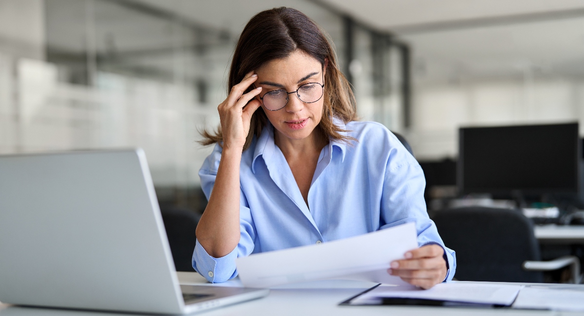 Worried business woman reading bad news in document at work