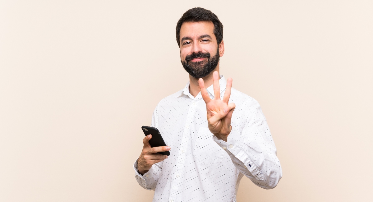 Man holding up three fingers with phone in his other hand