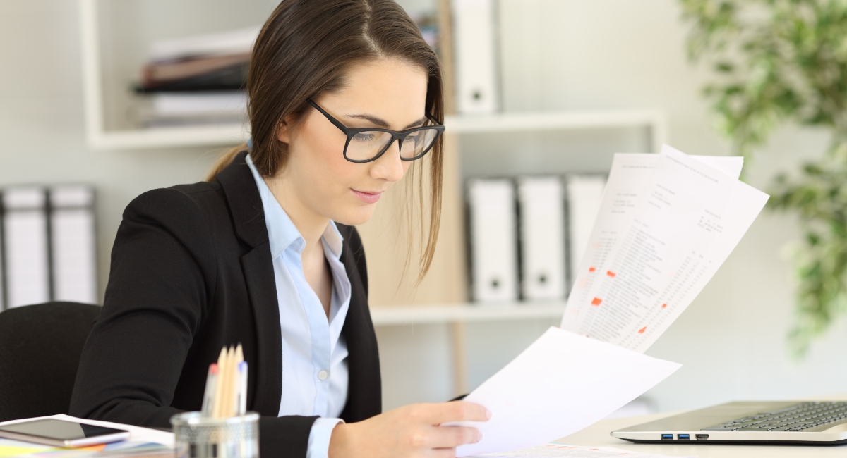 Adult business woman sitting at a desk comparing Guardian vs MassMutual paperwork