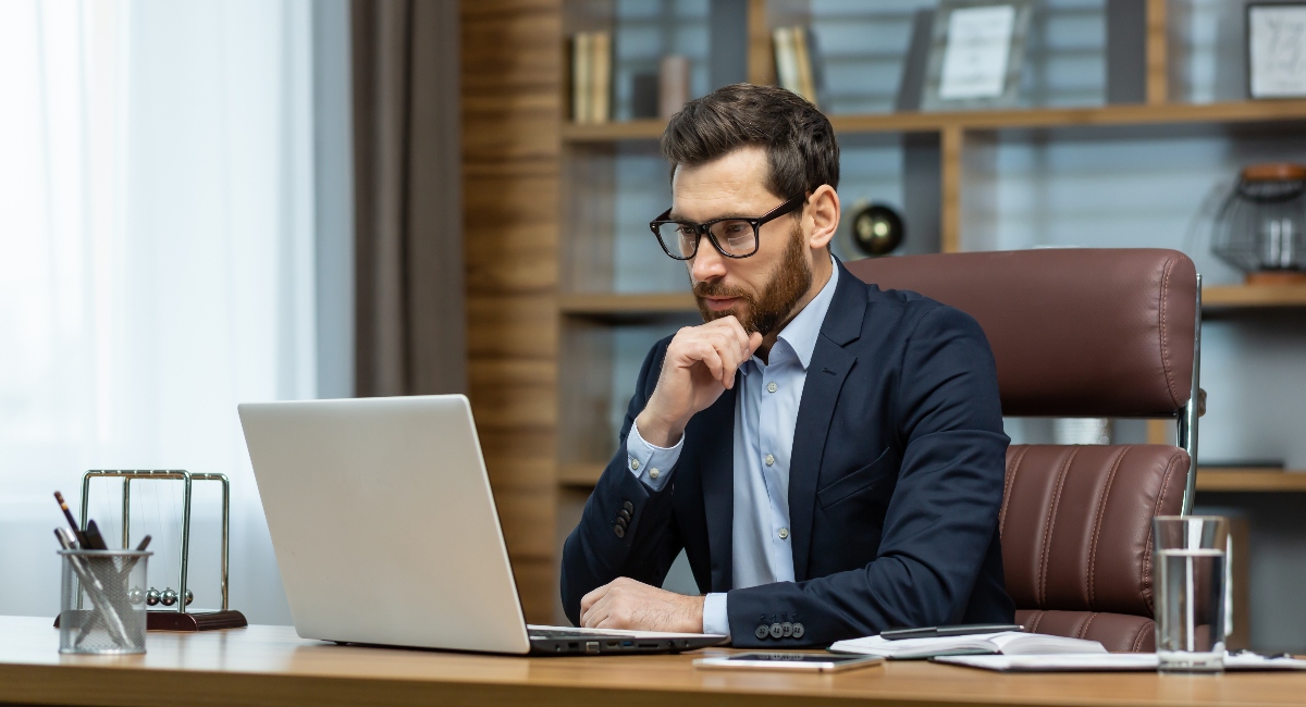 Businessman sitting at desk looking at laptop screen