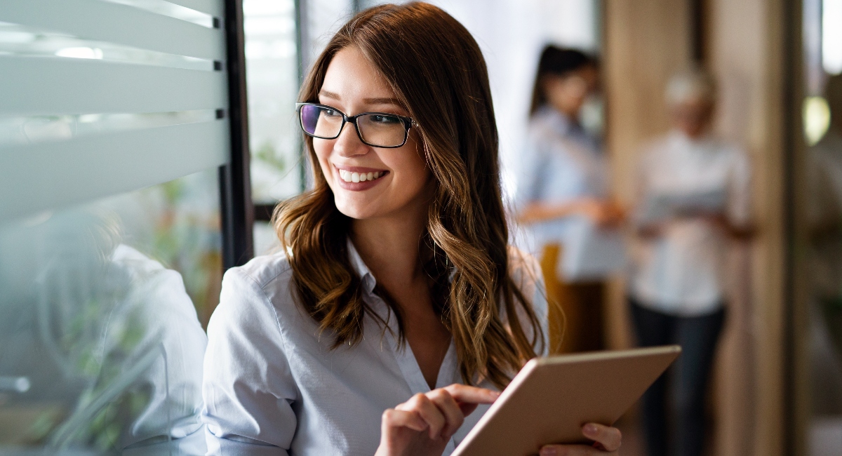 Young happy business woman working with tablet in corporate office