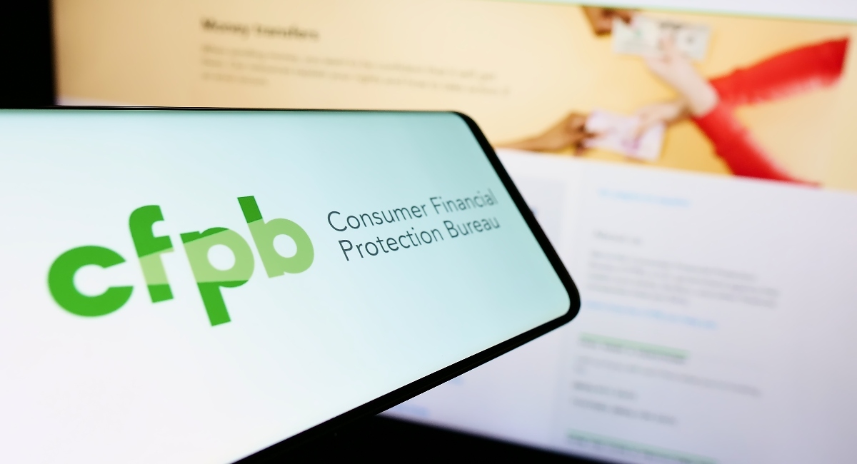 Cellphone with logo of US Consumer Financial Protection Bureau (CFPB) on screen in front of website