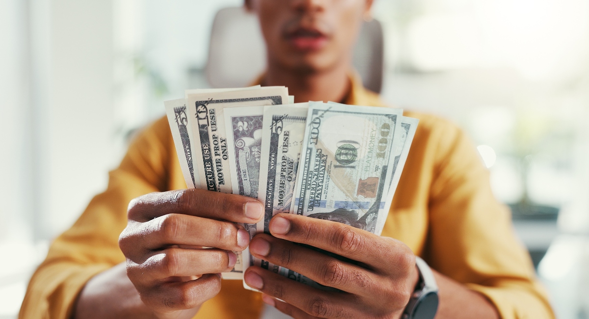 Hands holding cash, counting money in an office